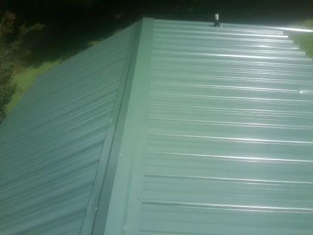 New green metal panels meeting at the ridge of a roof — Flat Roof Repair work by our crew in New Kensington