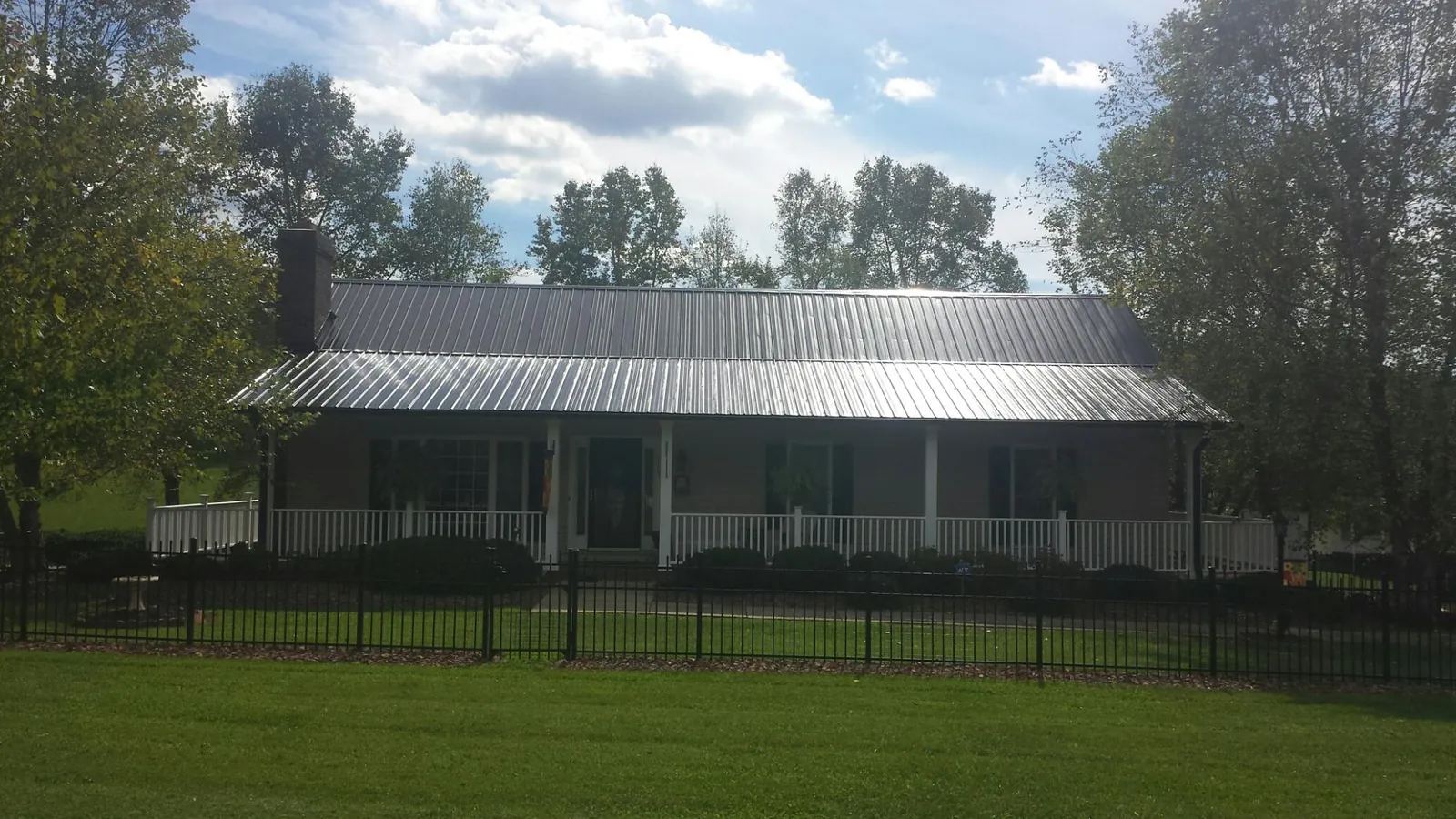 Gray metal roof on a brick ranch with a full width front porch — Gutter Guard Installation work by our crew in New Kensington