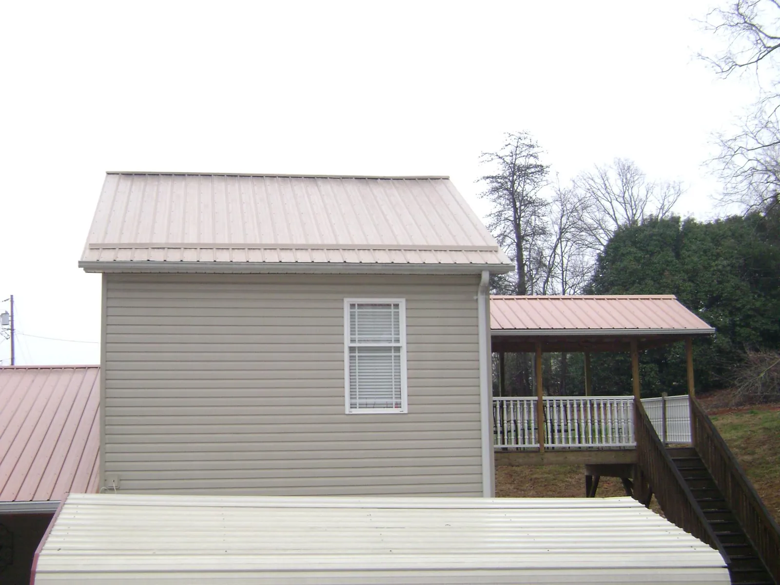 Tan metal roofs on a two story addition and attached porch, from a Roof Replacement job in New Kensington