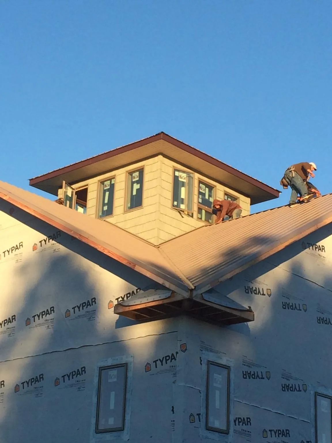 Roofers working around a rooftop cupola on a new metal roof at sunset — Roof Waterproofing in New Kensington by Roofing Brothers